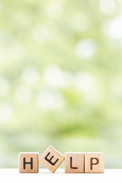 HELP word is written on wooden cubes on a green summer background Closeup of wooden elements