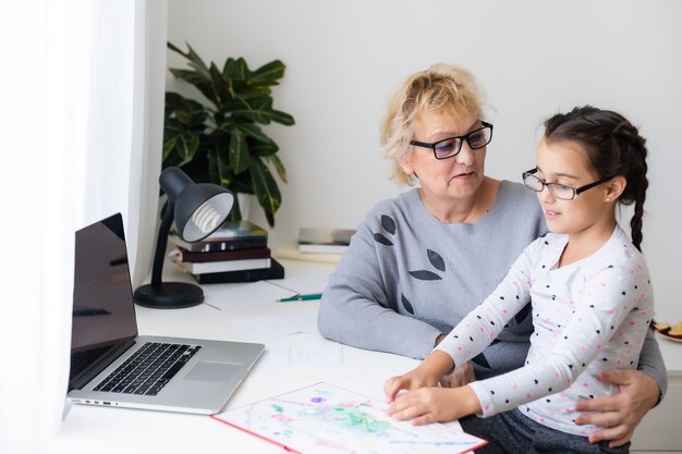 Helpful granny. Helpful loving granny assisting her cute granddaughter making homework