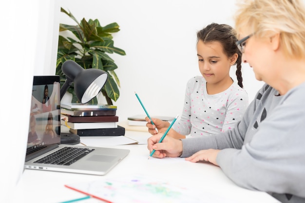 Helpful granny. Helpful loving granny assisting her cute granddaughter making homework