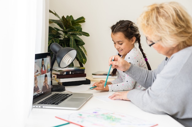 Helpful granny. Helpful loving granny assisting her cute granddaughter making homework