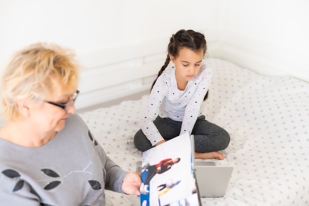 Helpful granny. Helpful loving granny assisting her cute granddaughter making homework