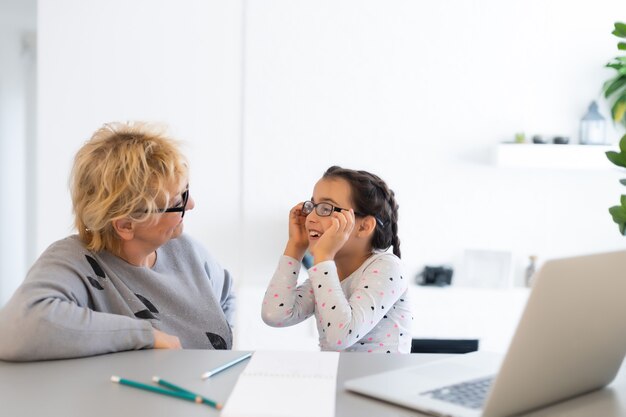 Helpful granny. Helpful loving granny assisting her cute granddaughter making homework