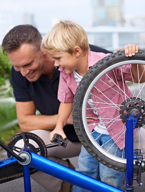 Hem leren over fietsonderhoud Een knappe vader die zijn zoon de verschillende onderdelen van een fiets laat zien