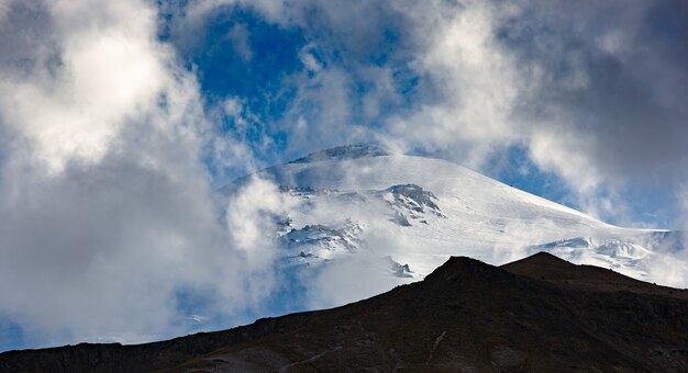 Hemel met wolken boven de besneeuwde top van Mount Elbrus, Noord-Kaukasus.