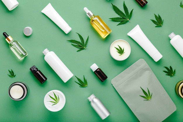 Hemp cbd oil serum in glass dropper bottle with cannabis leaves, Moisturizing cream, Serum, lotion, essential oil. Cannabis leaf with skincare cosmetic product Flat lay pattern on green background.