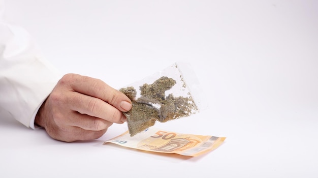 Hemp and drugs bag of marijuana in hand delivery gestare money white background