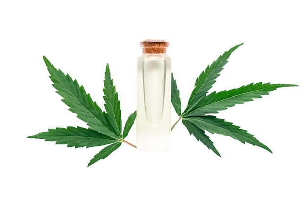 白い背景で隔離の大麻の葉とガラス瓶の麻油エッセンシャルオイル。スキンケア化粧品と大麻の葉