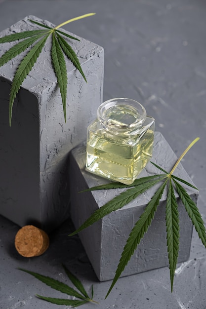 ガラス瓶と大麻の葉と灰色の背景に麻油