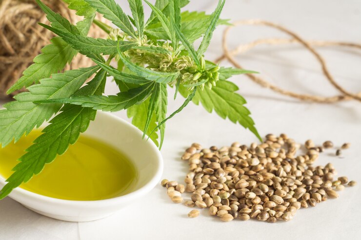 Photo hemp products concept. cannabis seed oil, skein and green plant on white background