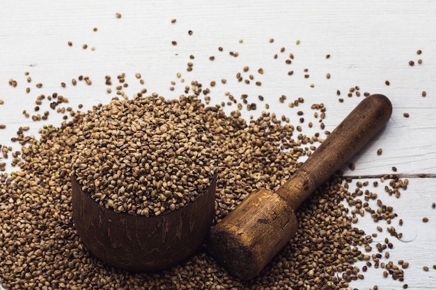 Hemp seeds in an old wooden mortar on a white