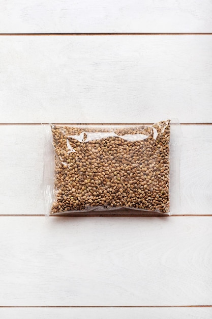 Hemp seeds in transparent packaging on a light wooden\
background mockup