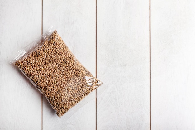 Hemp seeds in transparent packaging on a light wooden\
background mockup