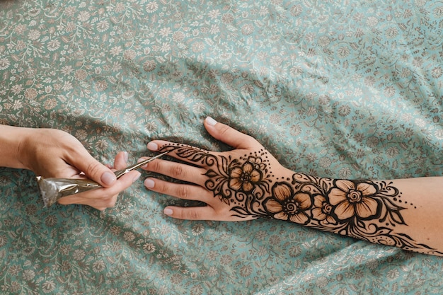 Henna tattoo on woman hands artist drawing arabic mehndi