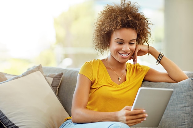 Her favourite online magazine keeps her entertained for hours Shot of a young woman using a digital tablet on a relaxing day at home