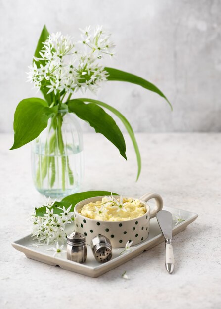 herb butter with wild garlic flowers lemon juice pepper and salt in a ceramic bowl