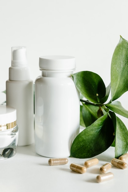Foto capsule di erbe e bottiglie bianche, concetto di sanità e bellezza.