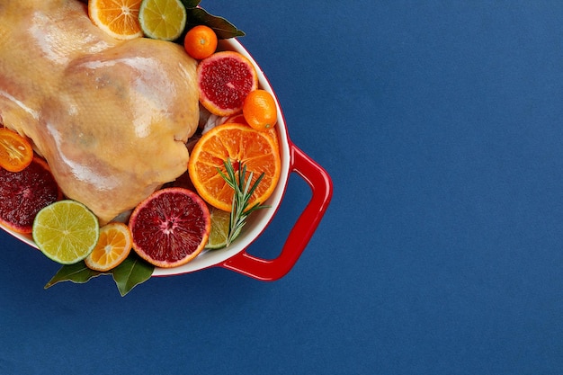 Herb and citrus oven roasted chicken Whole chicken in roasting tin with lemon and herbs ready for the oven Top view blank space