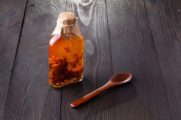 Herb-flavored oil on dark wood table