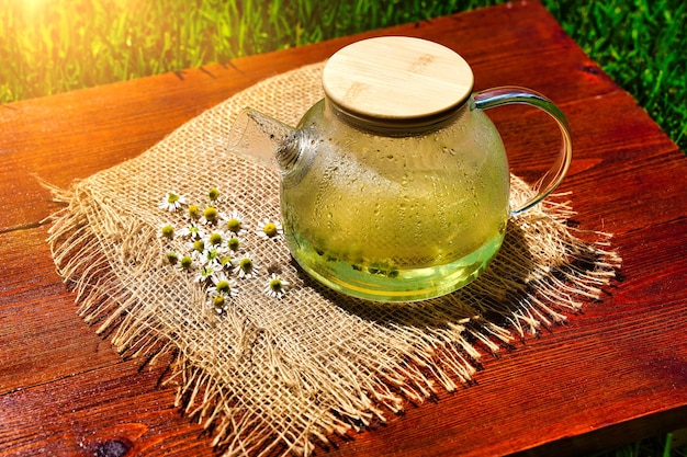 Herbal chamomile tea and chamomile flowers near teapot Rural or countryside background