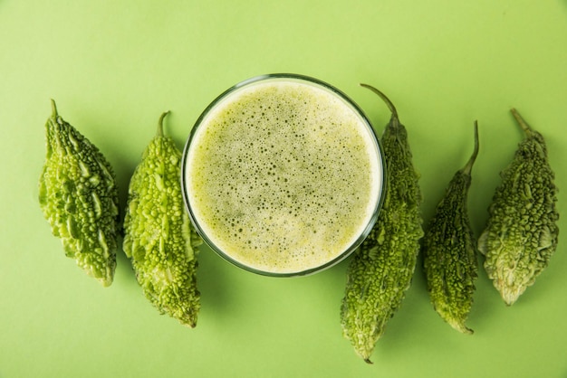 Herbal juice of Bitter gourd or Karela is the best natural medicine for diabetes. Whole bitter melons and Glass full of Juice kept over colourful or wooden background. Selective focus