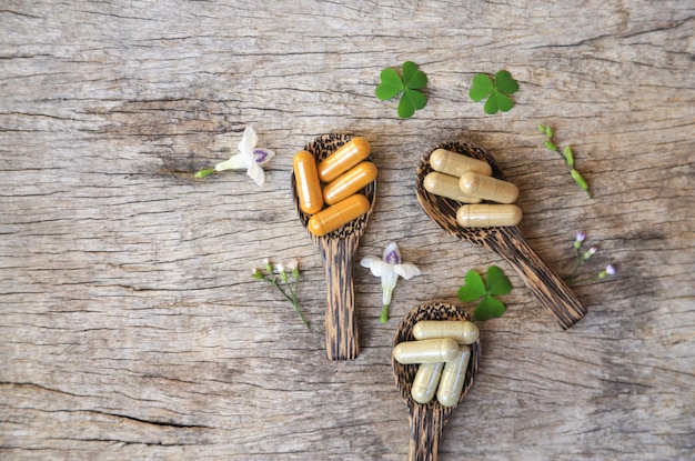 Herbal medicine in capsules from moringa leaf on rustic wooden\
table with copy space for medical background healthy eating with\
natural product for good living