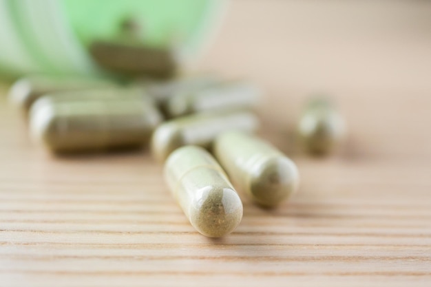 Herbal medicine capsules with bottle on wood table