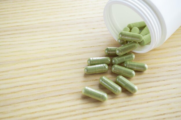 Herbal medicine capsules with bottle on wood table