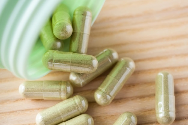 Herbal medicine capsules with bottle on wood table