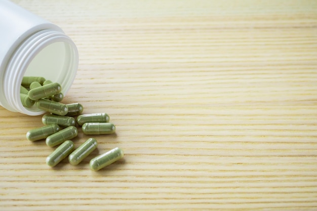 Herbal medicine capsules with bottle on wood table