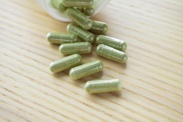 Herbal medicine capsules with bottle on wood table