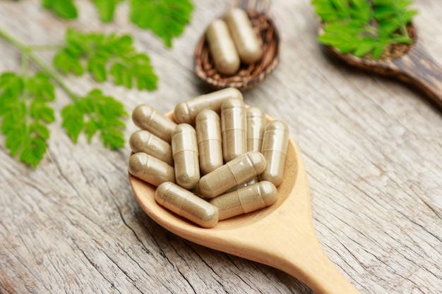 Herbal medicine in capsules on wooden spoon with herb