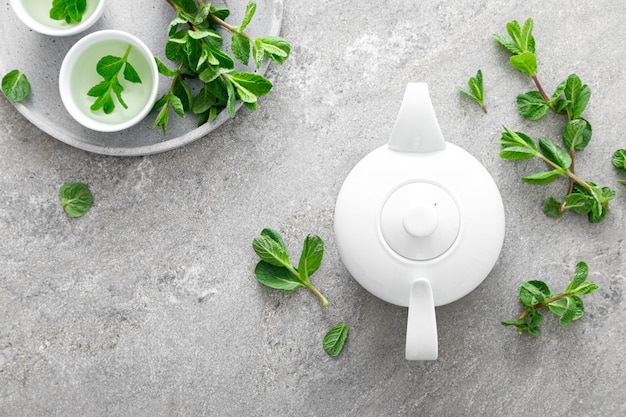 Фото Травяной мятный чай в чайнике и свежие листья полезный антиоксидантный напиток