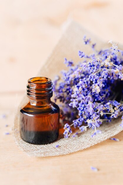 Herbal oil and lavender flowers on wooden background