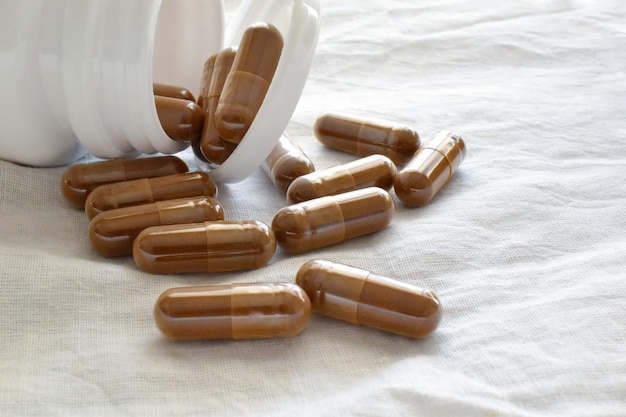 Herbal supplement capsules spilling out of a plastic bottle