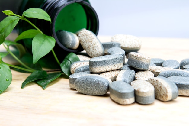 Herbal Supplement vitamin pills or tablets on wooden plate