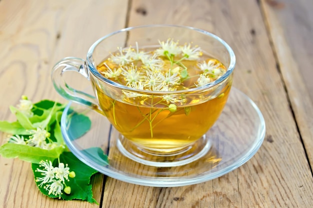 Herbal tea in a glass cup fresh linden flowers on a wooden boards background