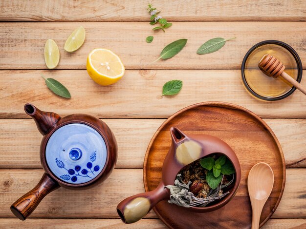 Herbal tea pot with fresh herbs sage peppermint dried chrysanthemum and lime slice on rustic wooden background