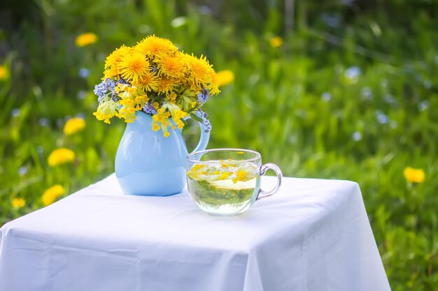 Herbal tea in a spring garden with yellow dandelion flowers blooming around