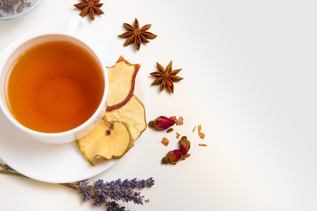 Herbal tea in white cup with ingredients on white background