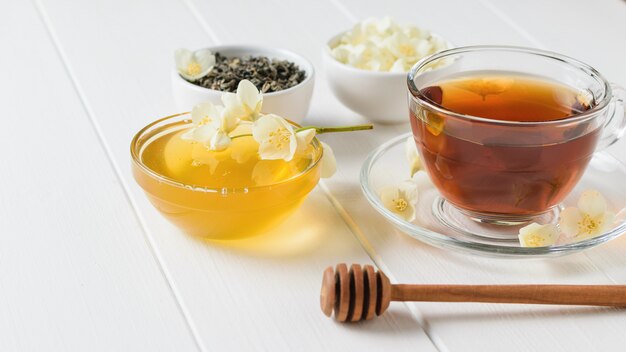 Herbal tea with Jasmine, honey and a wooden spoon on a white table.