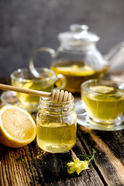 Herbal tea with lemon and honey in glass cup and teapot