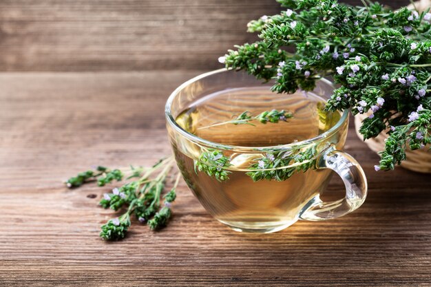 Herbal tea with thyme over rustic wooden background.