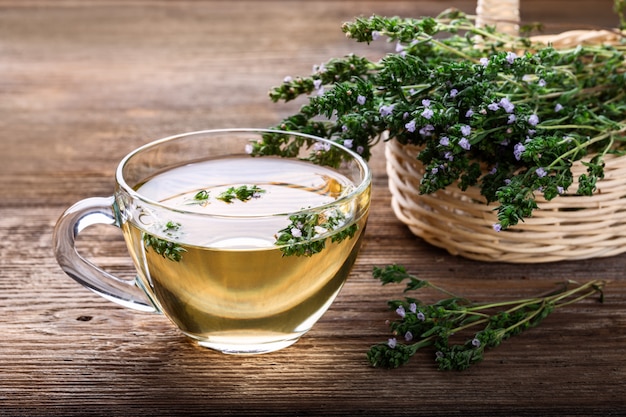 Herbal tea with thyme over rustic wooden background.