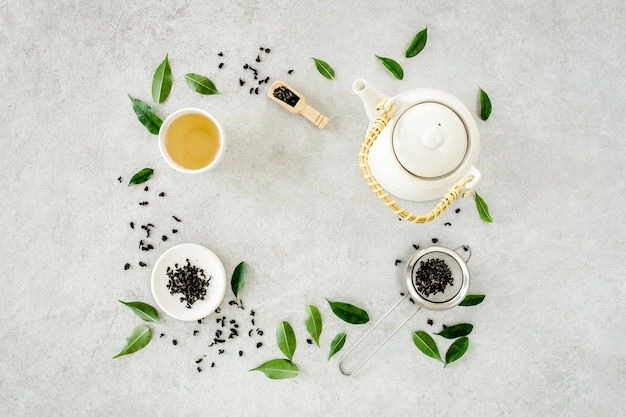 Herbal tea with two white tea cups and teapot with green tea leaves flat lay top view tea concept