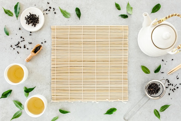 Herbal tea with two white tea cups and teapot with green tea leaves flat lay top view tea concept