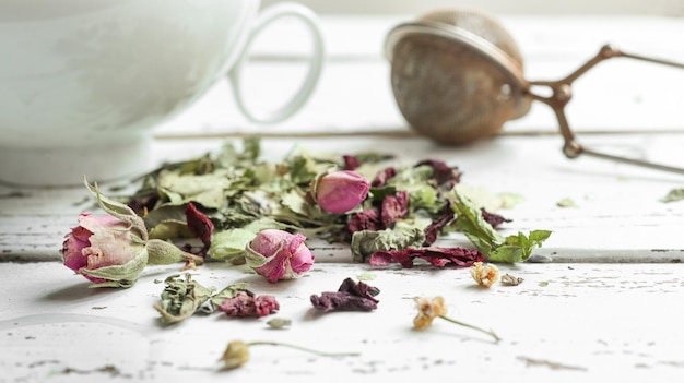 Herbal teal on a light wooden table a white cup and tea infuser spoon closeup