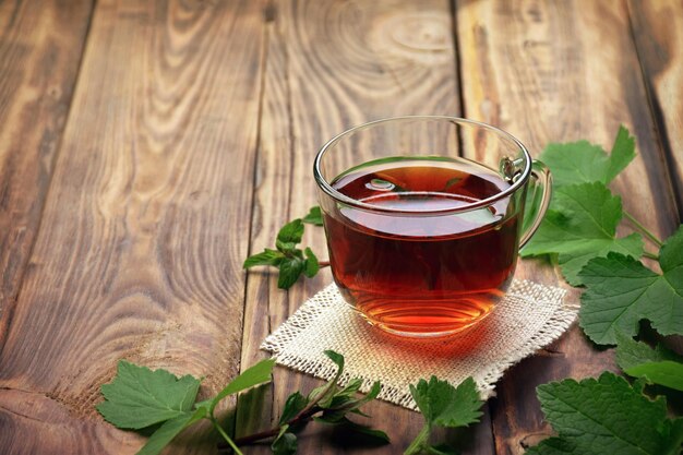 Foto herbal teamint leaftea in una tazza di vetro foglie di menta erbe tè e foglie di menta su sfondo di legno