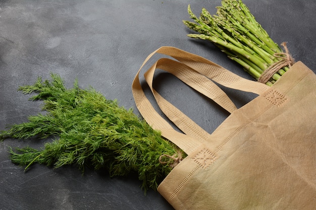 Herbruikbare afvalzak van textiel, gevuld met groene asperges en peterselie