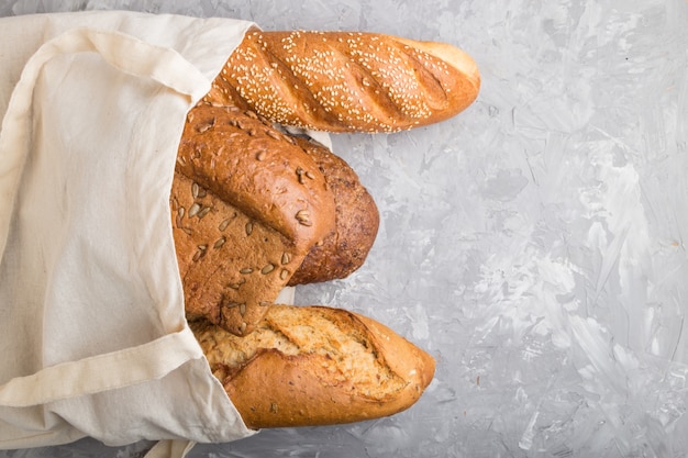 Herbruikbare boodschappentas met vers gebakken brood op een grijze concrete achtergrond. bovenaanzicht, kopie ruimte.