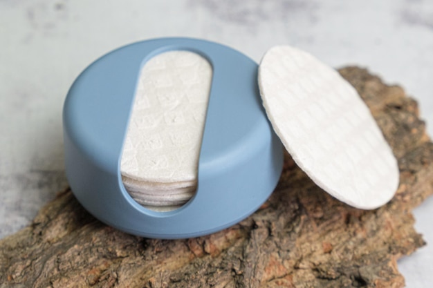 Herbruikbare cotton rounds make-up remover in een container gemaakt van gerecycled oceaanplastic op boomschors zero waste pads om milieuvervuiling te verminderen